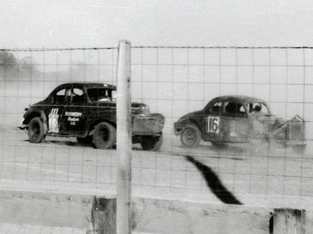 Cars speeding around Daytona Speedway during a race